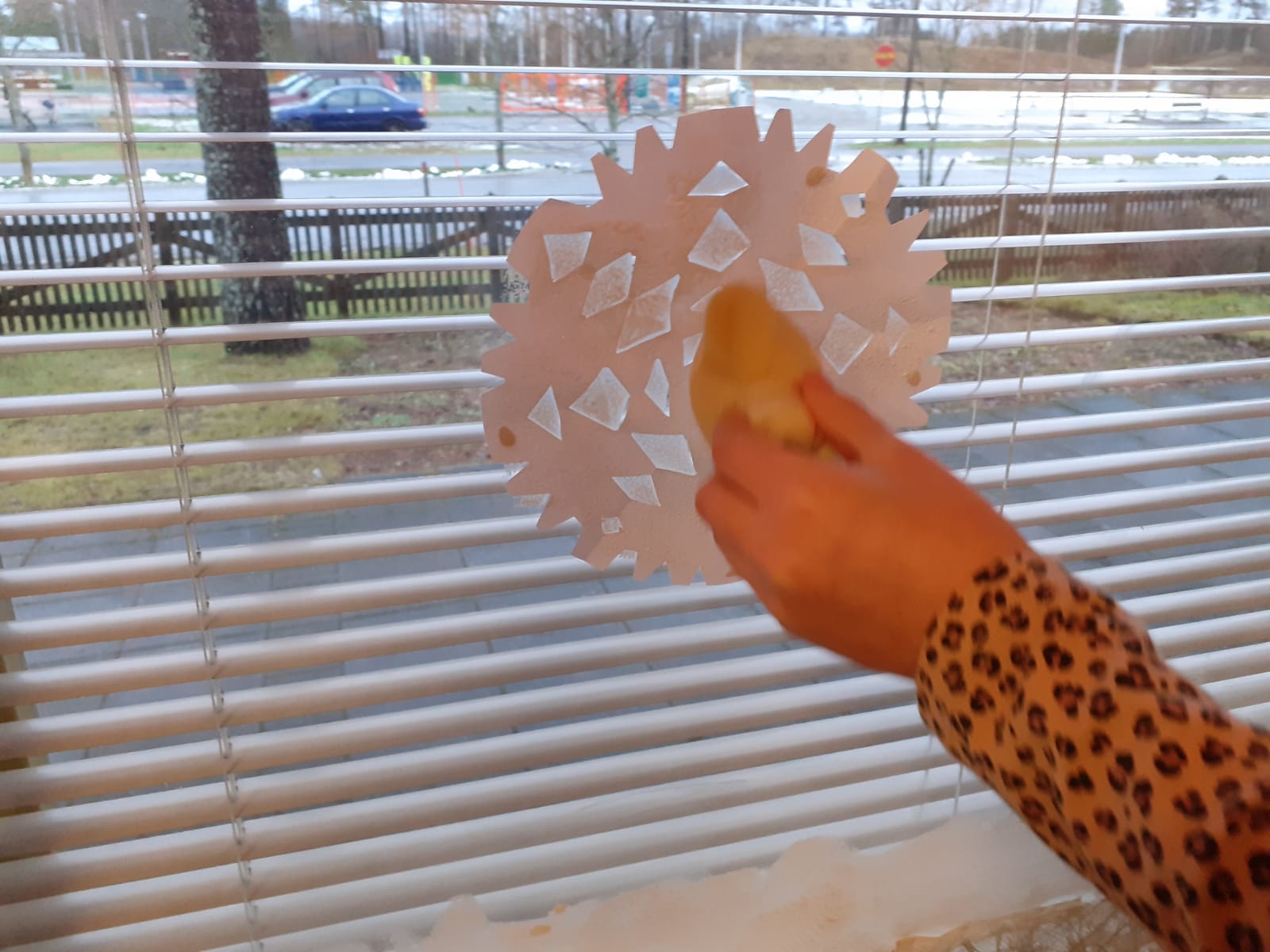 Lapsi tekemässä lumihiutalekoristelua ikkunaan