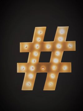 Hashtag-merkin muotoinen valaisin palaa mustaa taustaa vasten.