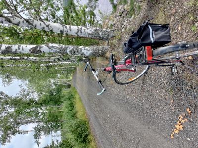 Polkupyörä on pysäköitynä soratien reunaan kesäisenä päivänä.