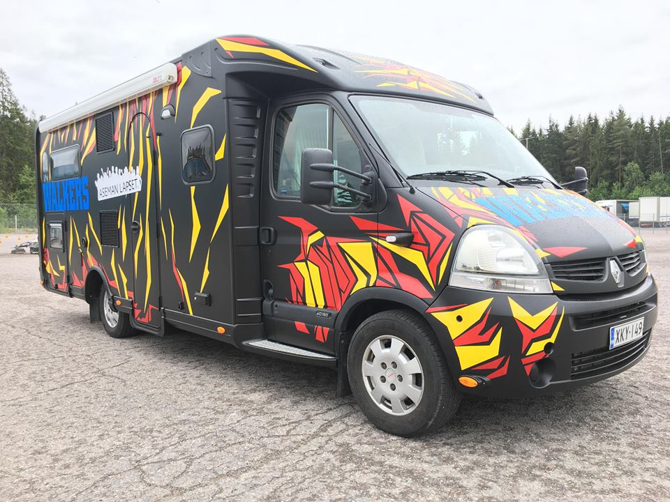 Musta matkailuauto, jossa on keltaisia ja punaisia "tiikerinjuovia" ja sininen teksti Walkers.