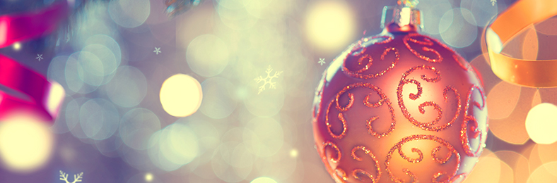 Kimalteella koristeltu joulukuusen pallo, taustalla muita joulukoristeita