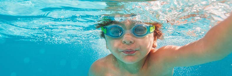 Veden alla otettu kuva lapsesta sukeltamassa uimalasit päässä.