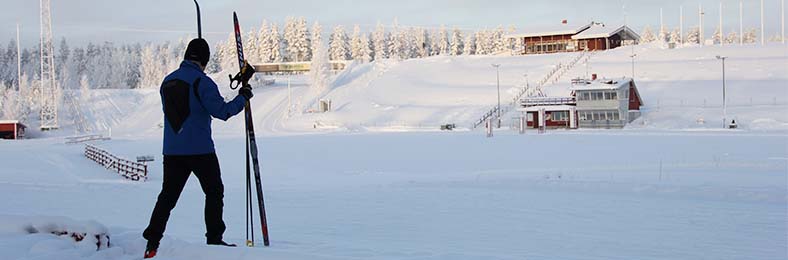 Pärnävaaran hiihtostadion talvella, yksi henkilö kantaa suksia etualalla