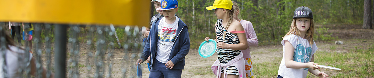 Lapset pelaavat frisbeegolfia.